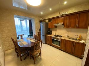 a kitchen with a table and a refrigerator and a table and chairs at Atlant luxury Big Family Perlina Apart on Golovna з двома санвузлами поряд з ТЦ Депот in Chernivtsi