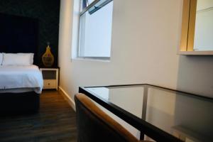 1 dormitorio con cama, ventana y mesa de cristal en Stay Ulo at The Apex on Smuts, en Johannesburgo