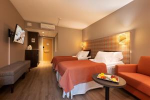 une chambre d'hôtel avec deux lits et un canapé dans l'établissement Spa Hotel Runni Iisalmi, à Iisalmi