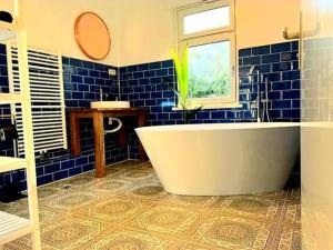uma casa de banho em azulejos azuis com uma banheira e uma janela em Romantik-Ferienhaus -Vier Sterne- idyllische Lage em Marienwerder