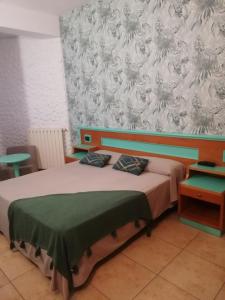 Schlafzimmer mit einem Bett mit einer grünen und weißen Tapete in der Unterkunft Hotel Esperia in Piombino