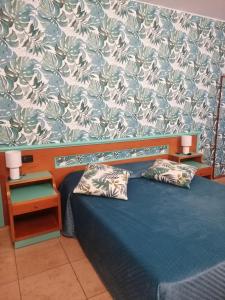 a bedroom with a blue bed with two pillows at Hotel Esperia in Piombino