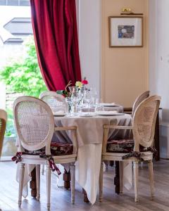 a dining room table with chairs and a red curtain at Hôtel le Centenaire in Les Eyzies-de-Tayac