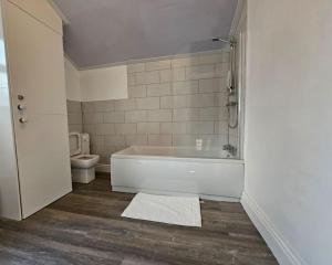 a bathroom with a bath tub and a toilet at Cheerful Home near Preston train station & Uclan in Preston