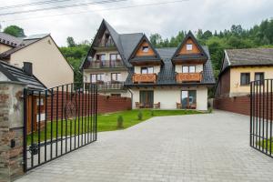 a large house with a gate in front of a driveway at Pod Reglami in Krościenko