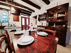 una cocina con una mesa de madera con platos y copas de vino en Guest house Nostalgia, en Gračišče