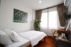 a bedroom with a bed and a desk and a window at Homie Non - โฮมมี่ นนท์ in Ban Bang Khwang