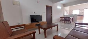 sala de estar con TV, sofá y mesas en Tranquil Serviced Apartments - Sarjapur, en Bangalore