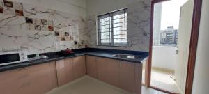 una pequeña cocina con fregadero y ventana en Tranquil Serviced Apartments - Sarjapur, en Bangalore
