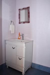 a white bathroom with a sink and a mirror at Home De francisco in Canacona