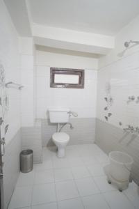 a white bathroom with a toilet and a sink at The yerpa Hotel in Kasol