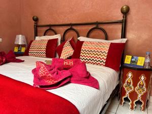 ein Bett mit roten Decken und Kissen darauf in der Unterkunft Riad khoya magnifique in Marrakesch
