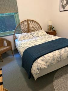 a bedroom with a bed with a blue blanket and a window at Butlers Guesthouse in Birregurra