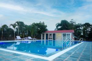 a swimming pool with a house in the background at Center Park Resort Pvt.Ltd in Sauraha
