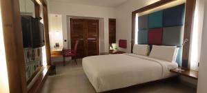 a bedroom with a large white bed and a television at The Promenade in Puducherry