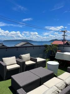 a patio with wicker chairs and tables and the ocean at ロハスResort宮浦 in Fukuoka