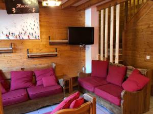 a living room with purple couches and a flat screen tv at Chalet Flocon 14p Les 2 alpes in Les Deux Alpes