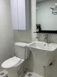 a white bathroom with a toilet and a sink at Maison de Haenggung in Suwon
