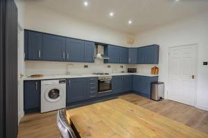 een keuken met blauwe kasten en een wasmachine bij Coastal Views Apartment Cleethorpes in Cleethorpes