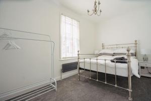 a white bedroom with a bed and a window at Coastal Views Apartment Cleethorpes in Cleethorpes