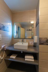 W łazience znajduje się umywalka i lustro. w obiekcie Logis Hôtel Le Rochelois w La Rochelle
