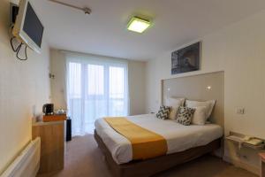 a bedroom with a bed with a television and a window at Logis Hôtel Le Rochelois in La Rochelle