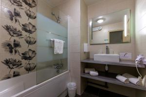 a bathroom with a tub and a sink and a mirror at Logis Hôtel Le Rochelois in La Rochelle
