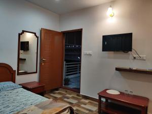 sypialnia z łóżkiem i telewizorem z płaskim ekranem na ścianie w obiekcie SkyHouse Homestay w mieście Mysuru