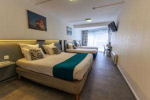 a hotel room with two beds and a table at Logis Hôtel Le Rochelois in La Rochelle