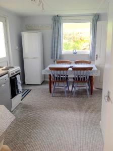 a kitchen with a table and two chairs and a refrigerator at Pant Glas in Cardigan