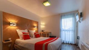 a hotel room with a large bed with red pillows at Logis Hôtel Le Rochelois in La Rochelle