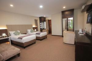 pokój hotelowy z 2 łóżkami i kanapą w obiekcie Grand Harvest Resort & Villas w mieście Banyuwangi