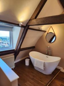 a bathroom with a large white tub in the attic at Rose & Star Cottage in Frome