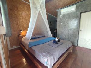 a bedroom with a bed with a mosquito net at Our Village Bungalows in Koh Mook