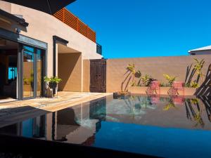 a swimming pool next to a house with an umbrella at Résidence Daniza in Saint-Pierre