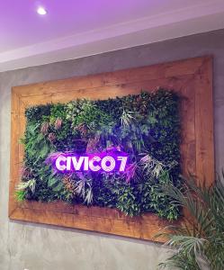 a neon sign on a wall with plants at civico settee in Rome