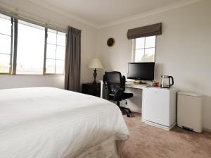 a bedroom with a bed and a desk with a computer at Tauranga Homestead Retreat in Tauranga