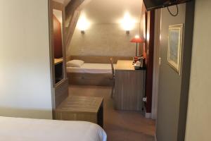 a small room with a bed and a desk and a mirror at Logis Hotels- Auberge de la Tour - Hôtel et restaurant in Sauzet