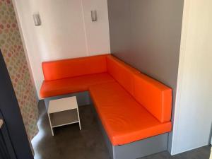 un banc orange dans une petite pièce avec un tabouret dans l'établissement Camping Costa Blanca, à El Campello