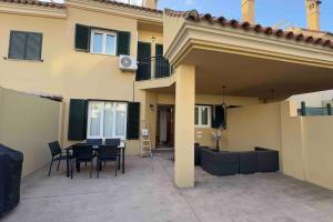 un patio con tavolo e sedie di fronte a una casa di Chalet Adosado Cerca Gibraltar a Alcaidesa