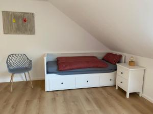 a bedroom with a white bed and a chair at Ferienwohnung Blumenau in Bad Berneck im Fichtelgebirge