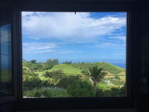 a window with a view of a green hill at Case Géranium 2* piscine chauffée in Saint-Joseph