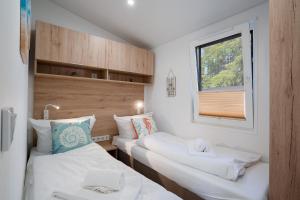2 camas individuais num pequeno quarto com uma janela. em Ostseecamp Lübecker Bucht Haus "Morgensonne" mit überdachter Veranda em Scharbeutz