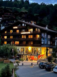 un hotel con coches estacionados en un estacionamiento en Hotel Lauberhorn - Home for Outdoor Activities, en Grindelwald