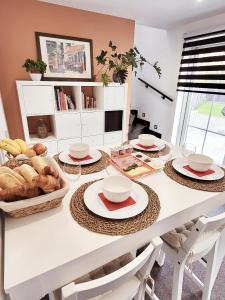a white dining room table with plates and baskets of bread at B&B Hoefkamp in Dilsen-Stokkem