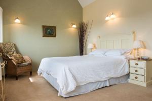 a bedroom with a large white bed and a chair at Unique Rural Stone dog friendly Barn Conversion in Okehampton
