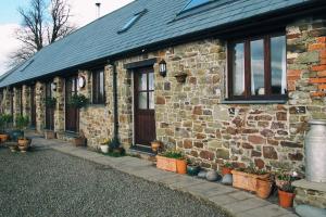 a brick house with potted plants in front of it at Unique Rural Stone dog friendly Barn Conversion in Okehampton