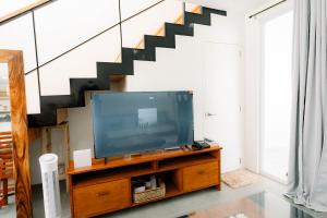 ein Wohnzimmer mit einem TV und einer Treppe in der Unterkunft R'Holistay Commune Village near WEDDING CHURCHES in Nasugbu