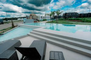 ein großer Pool mit zwei Stühlen und Tischen in der Unterkunft R'Holistay Commune Village near WEDDING CHURCHES in Nasugbu