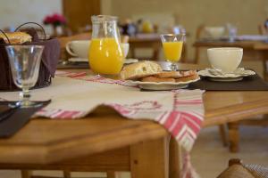 una mesa con pan, zumo de naranja y bebidas en La Grange de Boulaines, en Méru